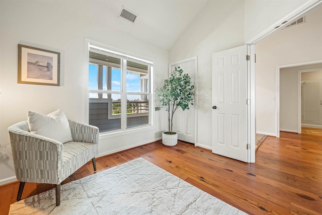 sitting room with vaulted ceiling, wood finished floors, visible vents, and baseboards