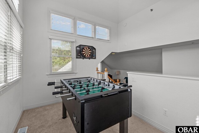 rec room featuring carpet flooring, baseboards, a high ceiling, and visible vents