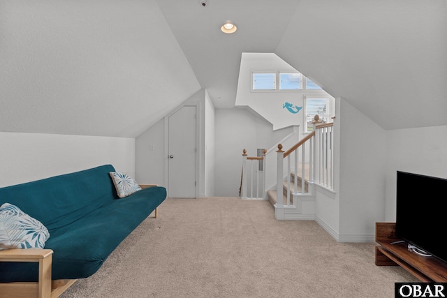 living area featuring lofted ceiling, carpet flooring, and baseboards