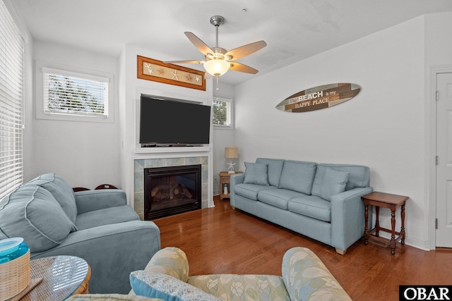 living area with a fireplace, a ceiling fan, and wood finished floors