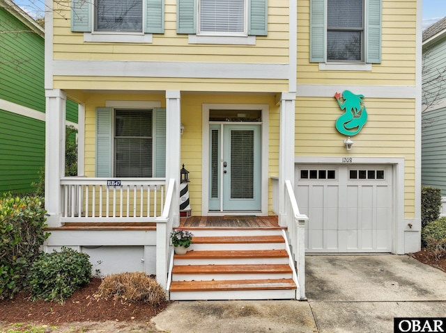 doorway to property with a porch, a garage, and driveway