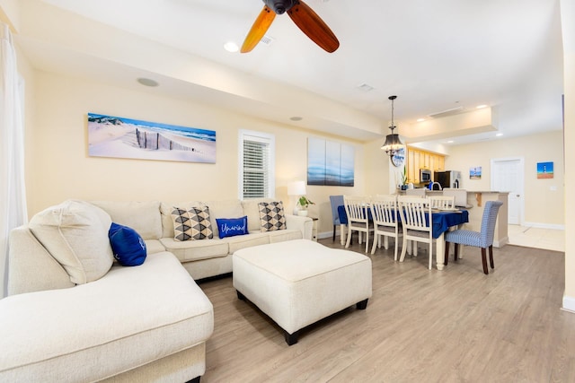 living room with recessed lighting, a raised ceiling, a ceiling fan, wood finished floors, and baseboards