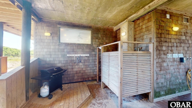 interior space with wooden ceiling, wooden walls, hardwood / wood-style floors, and concrete block wall