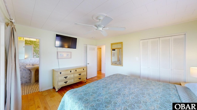 bedroom featuring a sink, ensuite bathroom, a closet, light wood-type flooring, and ceiling fan