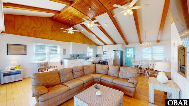living area with lofted ceiling with beams, light wood-style floors, and ceiling fan with notable chandelier