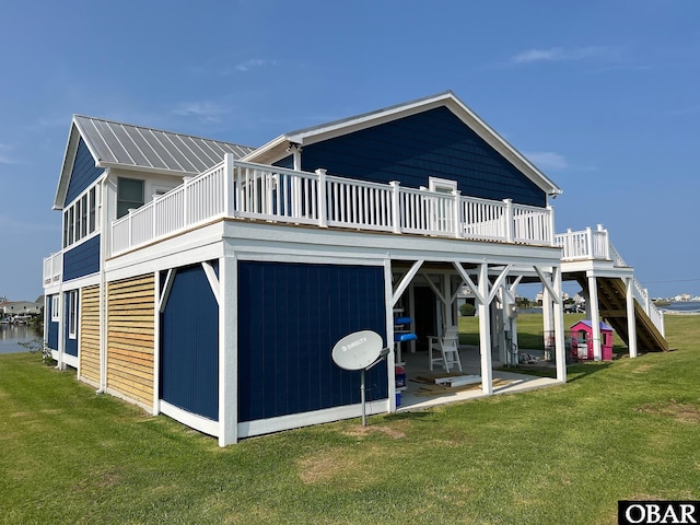 rear view of property featuring metal roof, a patio area, a lawn, and a deck