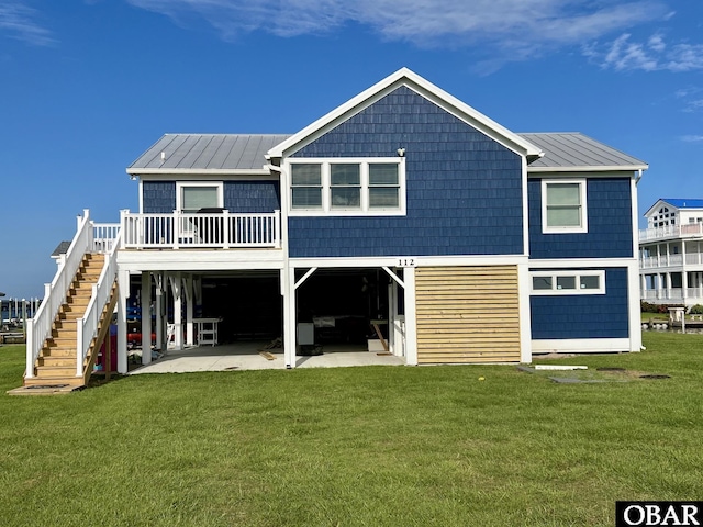 back of property with a lawn, stairway, metal roof, a patio area, and a carport