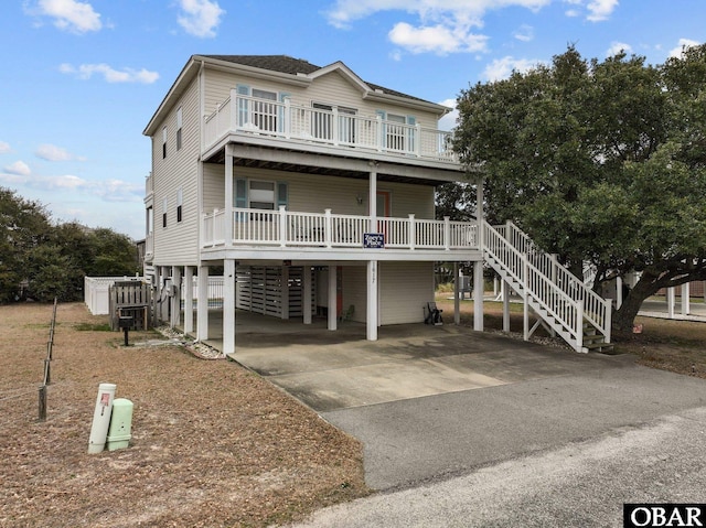 coastal home featuring driveway, a carport, and stairway