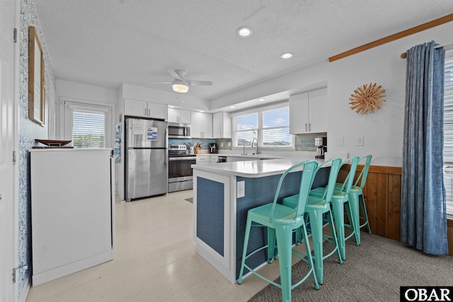 11 Pelican Watch Way Unit A/Lot11, Southern Shores, NC 27949 - kitchen featuring appliances with stainless steel finishes, a peninsula, a textured ceiling, a breakfast bar, and white cabinetry
