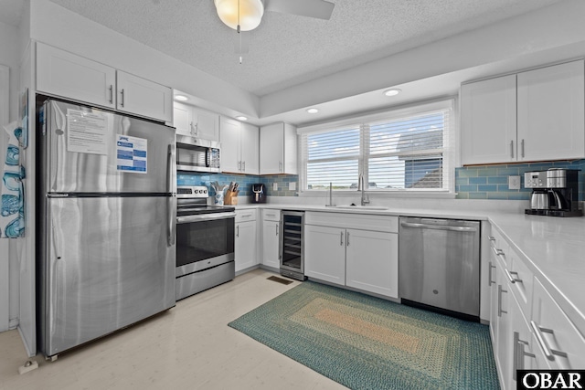 11 Pelican Watch Way Unit A/Lot11, Southern Shores, NC 27949 - kitchen with stainless steel appliances, a sink, a textured ceiling, wine cooler, and white cabinetry