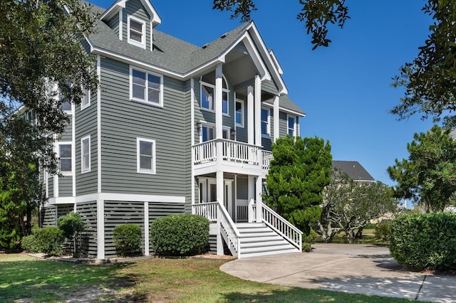 view of front of property with concrete driveway, a balcony, and a front yard