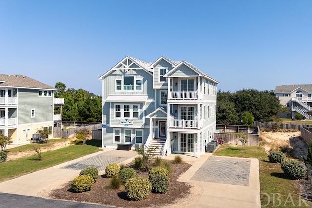 view of front of home with central AC, fence, driveway, a residential view, and board and batten siding