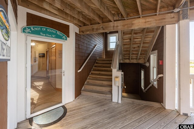 staircase featuring beamed ceiling, wooden walls, and wood finished floors