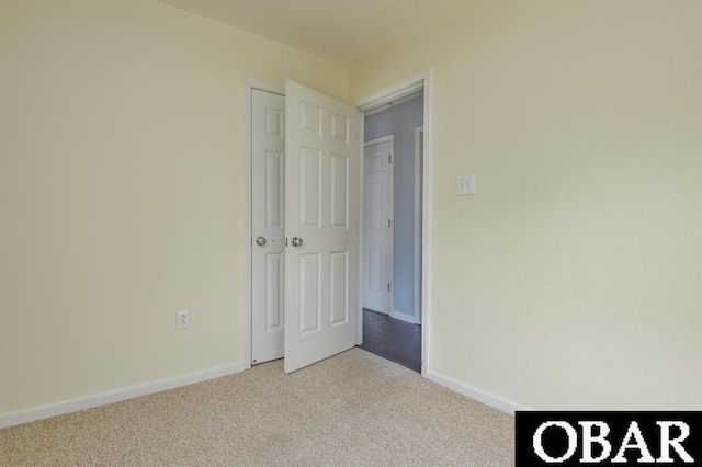 empty room featuring light carpet and baseboards