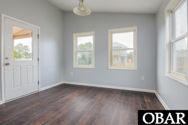 spare room featuring vaulted ceiling, dark wood-style flooring, and baseboards