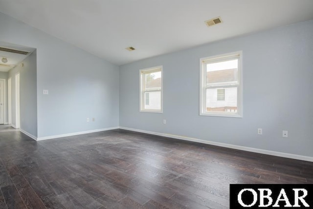 unfurnished room with dark wood-style flooring, visible vents, and baseboards