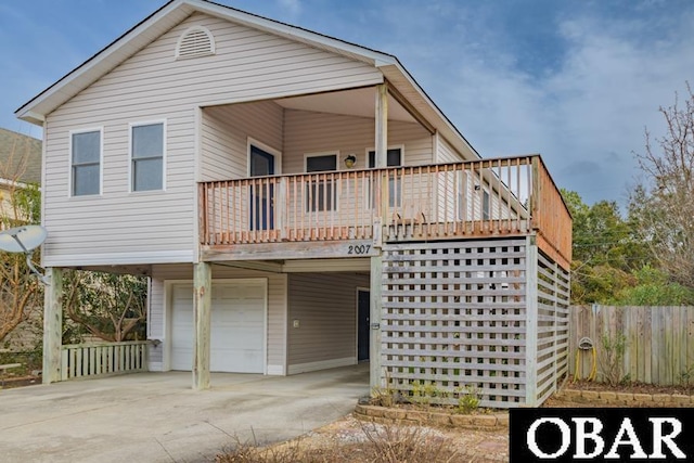 view of front of property featuring an attached garage, a balcony, fence, concrete driveway, and a carport