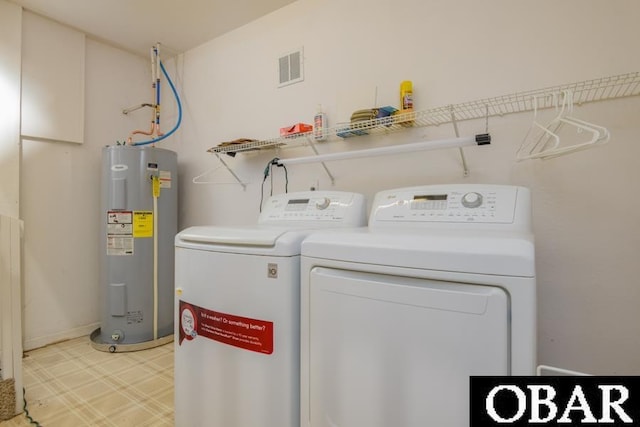 washroom featuring light floors, water heater, visible vents, washing machine and dryer, and laundry area