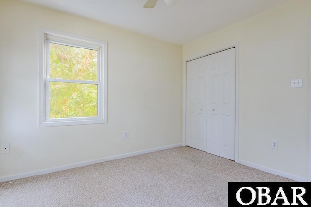 unfurnished bedroom with baseboards, a closet, a ceiling fan, and light colored carpet