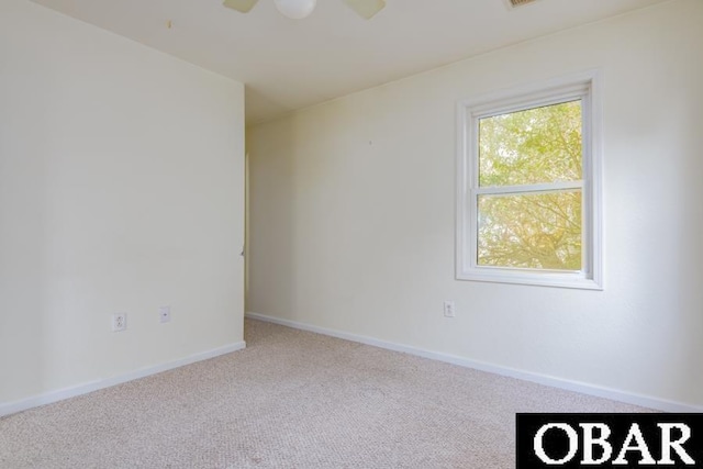 spare room featuring light carpet and baseboards