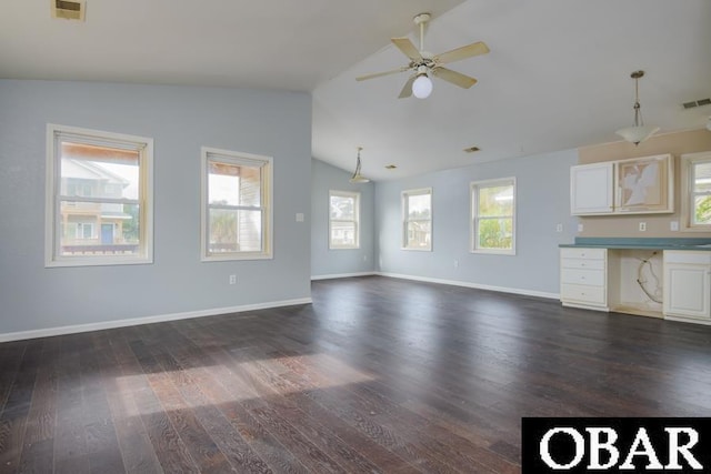 unfurnished living room with dark wood-style floors, a wealth of natural light, visible vents, and built in desk