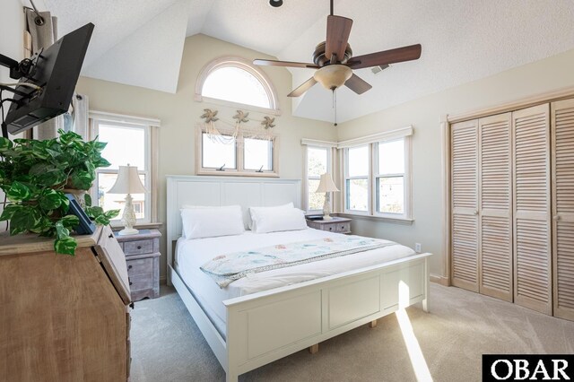 bedroom with lofted ceiling, a closet, light carpet, and a textured ceiling