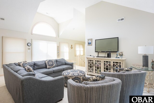 living area featuring high vaulted ceiling, visible vents, and light colored carpet