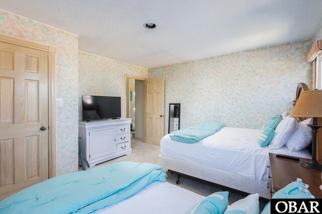 bedroom with wallpapered walls and a textured ceiling