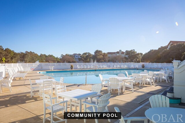 community pool with a patio area and fence