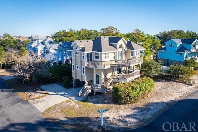 view of front facade with a shingled roof, stairway, a balcony, a residential view, and driveway