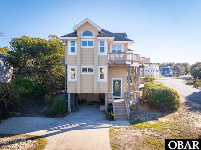 view of front of house with driveway, a carport, roof with shingles, and a balcony