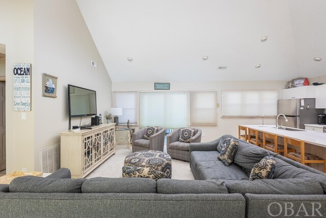 living area with light carpet, high vaulted ceiling, and visible vents