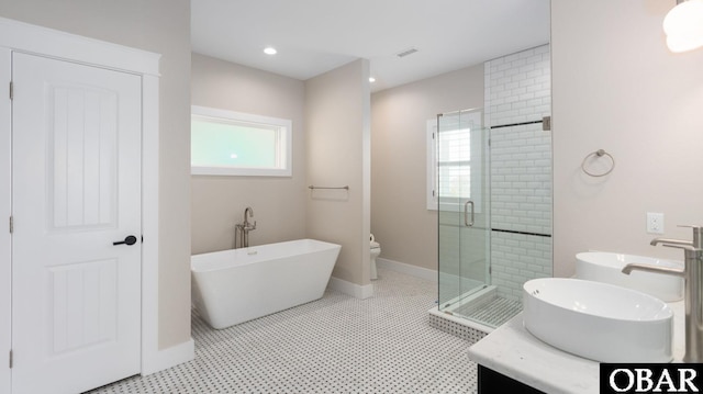 bathroom featuring a stall shower, a sink, plenty of natural light, and a freestanding bath