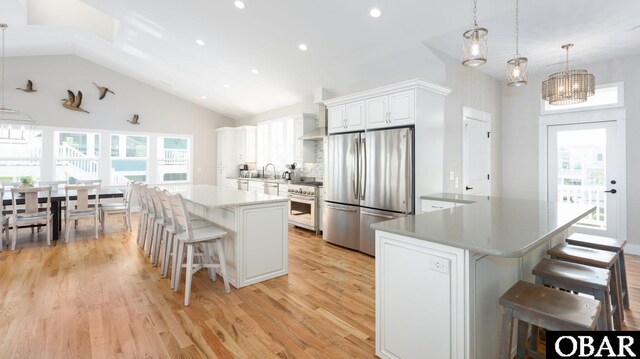 kitchen with a breakfast bar area, white cabinetry, hanging light fixtures, appliances with stainless steel finishes, and light countertops