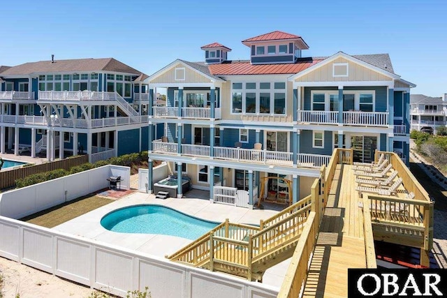 rear view of property featuring a fenced in pool, board and batten siding, a standing seam roof, a fenced backyard, and stairs