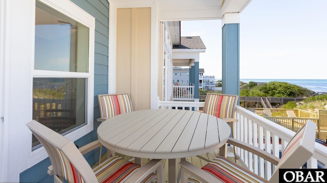 balcony with outdoor dining space and a water view