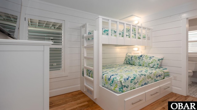 bedroom with light wood-style floors and wooden walls