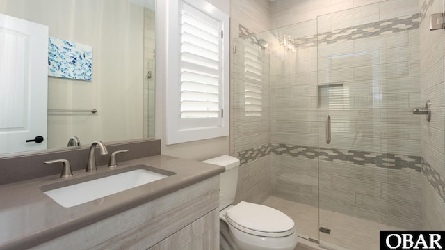 bathroom featuring toilet, a shower stall, and vanity