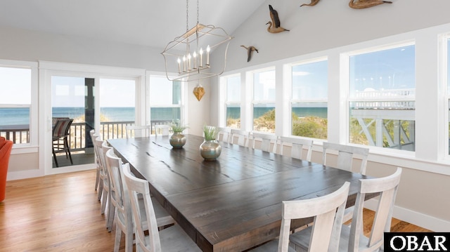 sunroom / solarium with lofted ceiling, a water view, and a notable chandelier