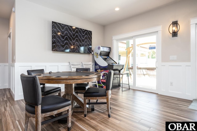 dining room with a wainscoted wall, a decorative wall, wood finished floors, and recessed lighting