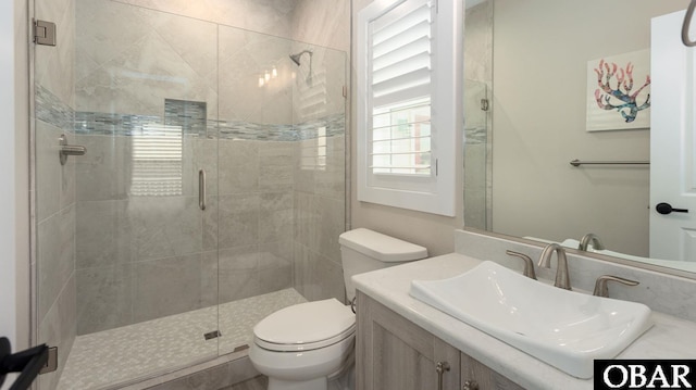 bathroom with toilet, a shower stall, and vanity