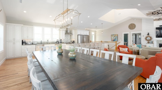 dining space with lofted ceiling, light wood-type flooring, a fireplace, and recessed lighting