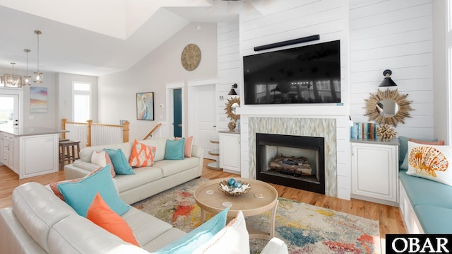 living room featuring light wood-type flooring, vaulted ceiling, and a fireplace