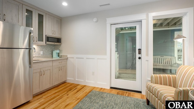 kitchen with visible vents, glass insert cabinets, appliances with stainless steel finishes, light countertops, and light wood-type flooring