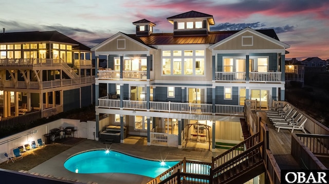 back of property with a fenced in pool, a patio, stairway, metal roof, and a standing seam roof