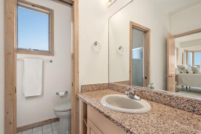 bathroom with toilet, plenty of natural light, tile patterned flooring, and vanity