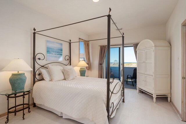 bedroom with access to outside, a water view, wood finished floors, and baseboards