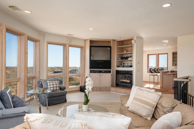 living room with visible vents, a fireplace with raised hearth, and recessed lighting