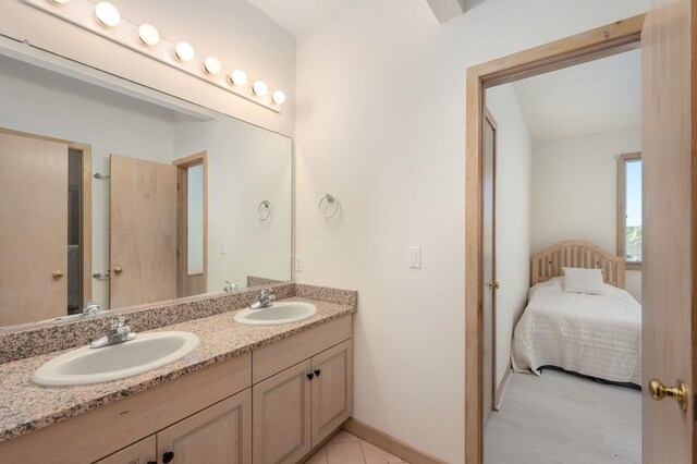 bathroom featuring baseboards, connected bathroom, a sink, and double vanity