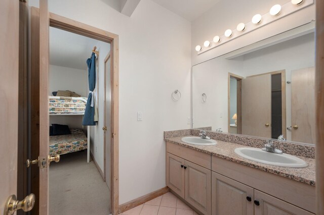 ensuite bathroom featuring double vanity, ensuite bath, a sink, and baseboards